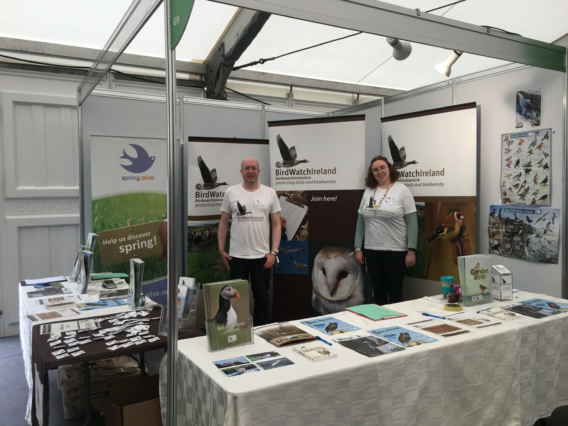A man and a woman behind a stand for BirdWatch Ireland. At Bord Bia's Bloom festival in Phoenix Park Dublin.